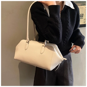Chic cream leather bowling bag featuring pebble grain texture and dual shoulder straps