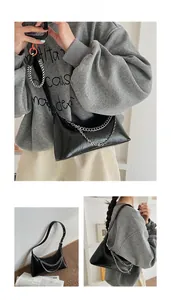 Detail view of glossy black leather shoulder bag with decorative silver metal chains