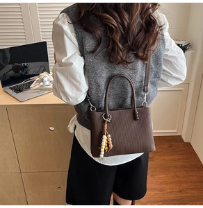 Détail du sac cabas marron foncé avec texture verticale et pompon à perles stylé