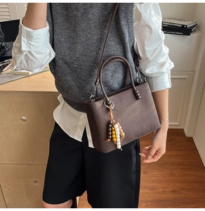 Détail du sac à main marron plissé avec pendentif en perles et bandoulière réglable
