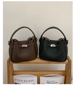 Gros plan de sacs seaux en cuir grainé avec boucles rotatives argentées sur étagère bois