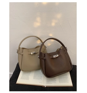 Détail de sacs seaux en cuir grainé avec fermoirs rotatifs métalliques en deux couleurs