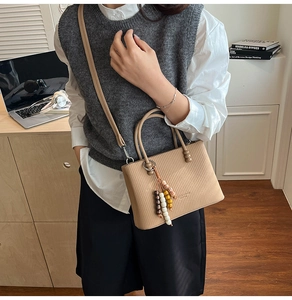 Détail du sac cabas kaki texturé avec poignée ronde en métal et pompon perlé chic