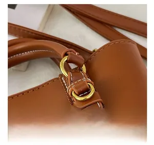 Detail of brown leather bag showing white contrast stitching and gold metal hardware