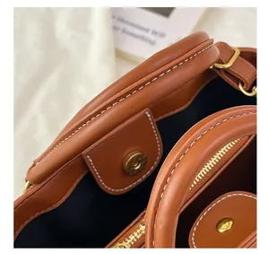 Detail of caramel leather bucket bag featuring magnetic closure and golden hardware
