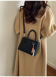 Détail du sac à main noir plissé vertical avec breloque bohème et bandoulière fine