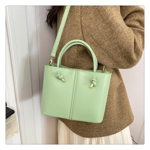 Detailaufnahme der hellgrünen Beuteltasche mit Goldbeschlägen und Lederknoten-Deko