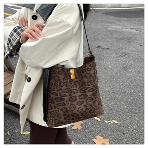 Detail of leopard print bucket bag with gold twist lock on a beige trench coat