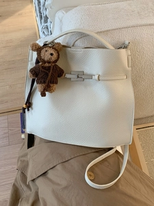 Ivory lychee leather bucket bag with silver lock and brown crochet bear charm
