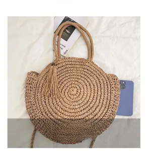 Detail show of woven straw bag with round handles and tassels for beach vacations