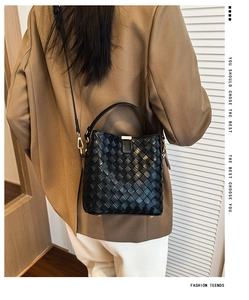 Détail du sac seau en cuir tressé noir avec boucle dorée et texture raffinée