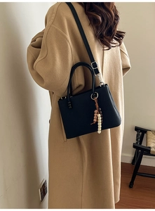 Vue détaillée du sac cabas noir à rayures verticales avec accessoire de perles élégant