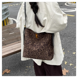 Detail view of leopard print bucket bag with gold twist lock and adjustable strap