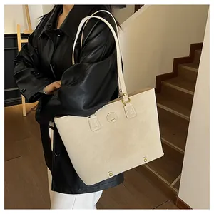 Detailansicht der cremefarbenen Shopper-Tasche mit Metall-Logo und Lederstruktur
