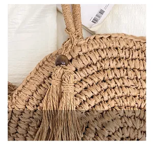 Detailed macro view of woven straw beach bag featuring wooden bead and twin tassels