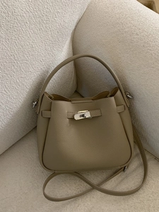 Sac seau kaki à motif litchi avec fermoir argenté sur un canapé en velours blanc