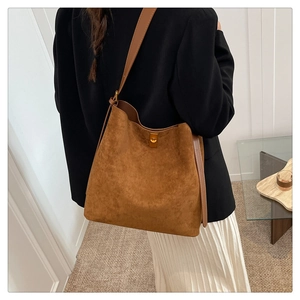 Detail of brown suede bucket bag featuring golden metal clasp and smooth leather strap