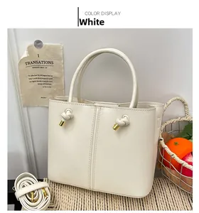 Detailansicht einer weißen Leder-Tote-Bag mit Knotendetails und goldenen Metallspitzen