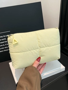 Quilted light yellow cloud clutch bag with padded texture and triangle zipper charm