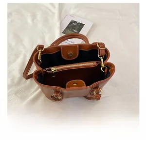 Internal view of brown leather bucket bag showing compartments and gold hardware detail
