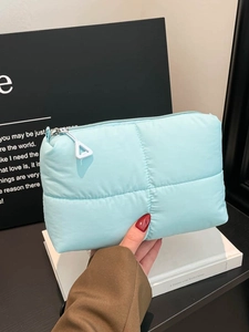 Quilted cloud puffer clutch bag in light blue with silver zipper for phone storage