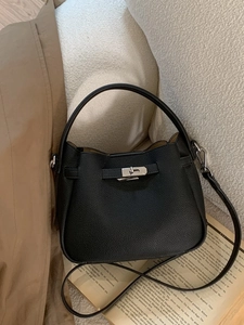 Sac seau élégant en cuir grainé noir avec boucle argentée sur un canapé beige
