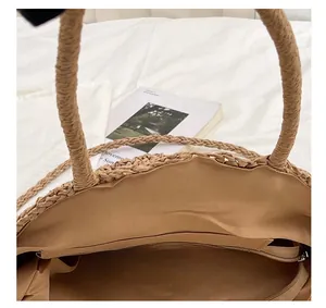 Detail showing wide opening of straw tote bag with inner zipper pocket for storage