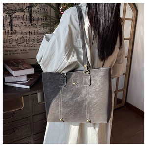 Detail der grauen Vintage-Leder-Einkaufstasche mit Kontrastnähten und goldenen Ringen