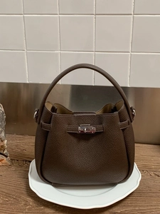 Sac seau en cuir grainé marron foncé avec boucles argentées sur un plateau blanc