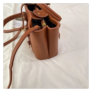 Detail of brown leather bucket bag with white contrast stitching and zip closure