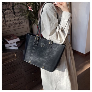 Detail der schwarzen Shopper Tasche mit weißen Kontrastnähten und goldenen Ring-Beschlägen