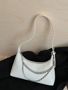 Chic white pleated crescent hobo bag with silver chain straps on a stylish wood background