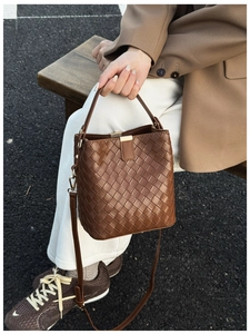 Détail du sac seau tressé marron foncé avec poignée supérieure et bandoulière chic