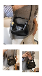 Detail of black glossy hobo bag with gold heart pendant and detachable shoulder strap