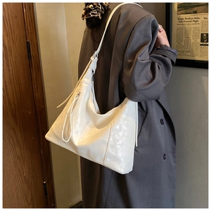 Détail du sac seau en cuir blanc montrant la fermeture éclair latérale et la lanière déco