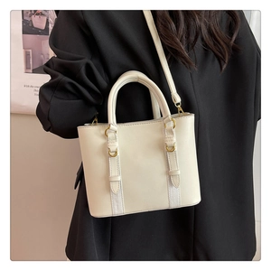 Detail of a creamy white PU leather bucket bag with metal rings and a sleek shoulder strap