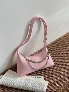 Chic pink pleated underarm bag with silver chain detail and adjustable strap on a woven mat