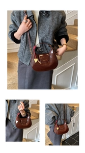 Detail view of smooth dark brown leather crescent bag with heart pendant ornament