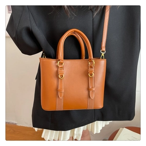 Detail showing high-quality tan bucket bag with white stitching and gold hardware buckle