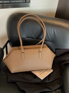 Chic khaki lychee pattern leather underarm bag with long straps on black leather chair