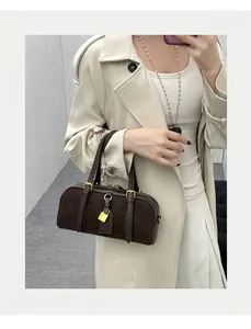 Detail of dark brown leather Boston handbag featuring gold padlock and vintage straps