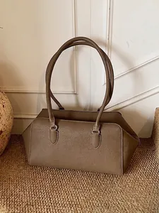 Taupe pebbled leather shoulder bag with long handles in a minimalist home setting