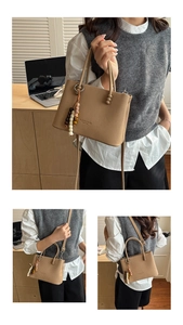 Detail of light brown striped tote bag showing wood bead tassel and leather texture