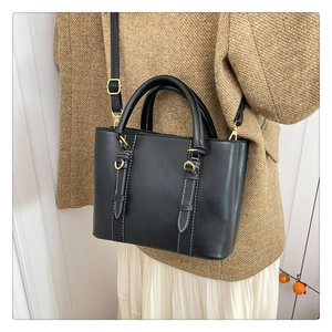 Detail of black leather bucket bag with white contrast stitching and gold hardware