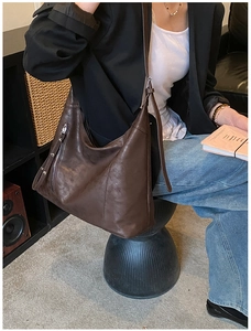 Vue détaillée du sac seau en cuir marron foncé avec fermeture éclair latérale et sangle