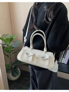 Close-up of beige bowling shoulder bag with dual front pockets and silver ring buckles
