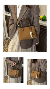 Detailed view of brown vertical embossed square bag with wooden bead charm and long strap