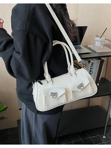 Macro detail of white leather Boston bag featuring two front pockets and silver buckles