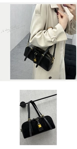 Detail of black Boston bag with pebbled leather texture and gold lock hardware charm