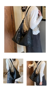 Détail du sac hobo en cuir noir montrant les fermetures éclair et les rivets latéraux